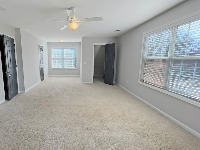 interior space featuring a ceiling fan, baseboards, light colored carpet, and visible vents