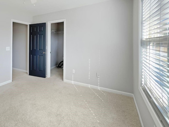 unfurnished bedroom with baseboards, carpet, a walk in closet, and a closet