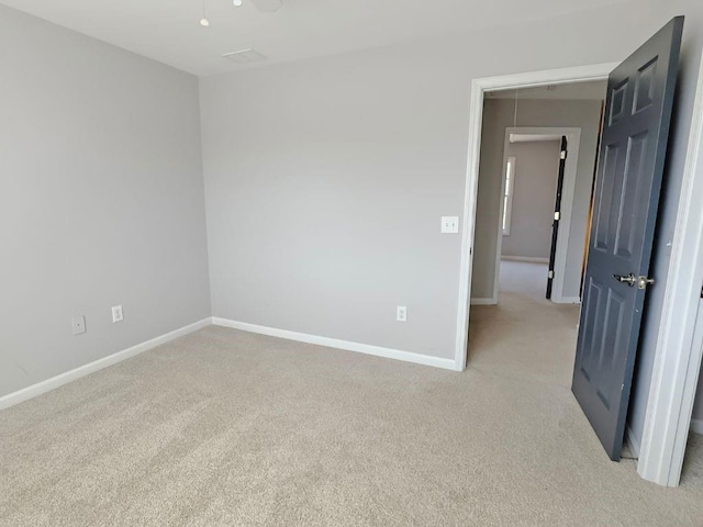 unfurnished room with baseboards and light carpet