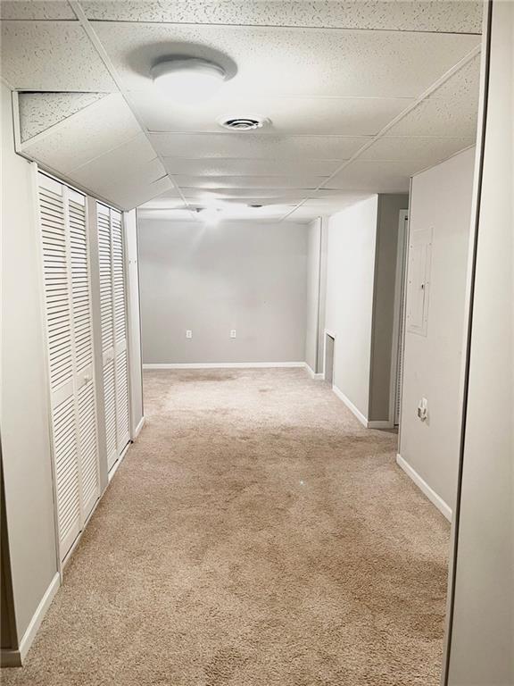 corridor with baseboards and light colored carpet