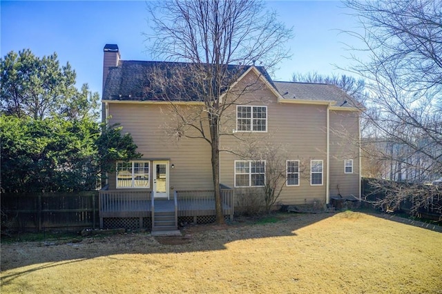 rear view of house with a lawn, fence, a chimney, and a deck