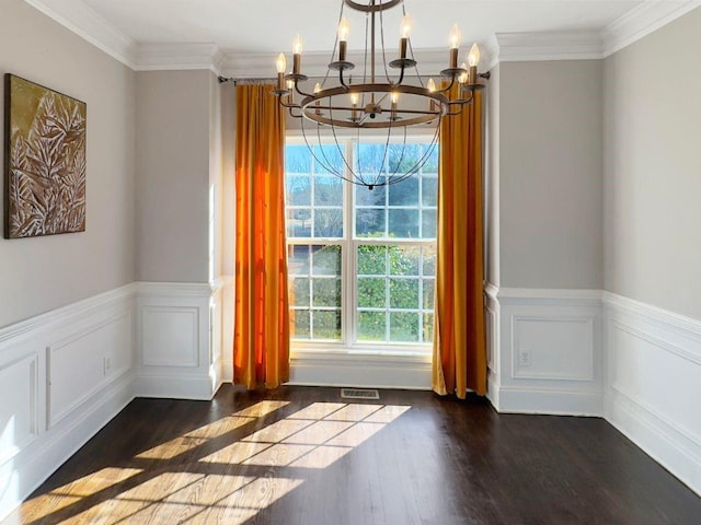 unfurnished dining area featuring visible vents, crown molding, wood finished floors, a wainscoted wall, and a chandelier