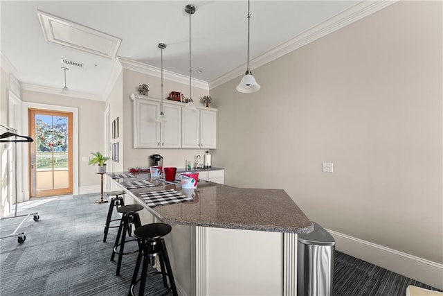 kitchen featuring a breakfast bar area, dark colored carpet, ornamental molding, pendant lighting, and white cabinets