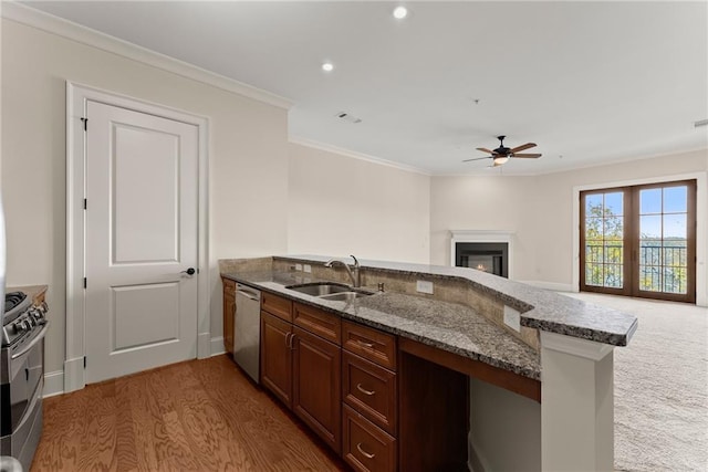 kitchen featuring sink, dark stone countertops, ornamental molding, kitchen peninsula, and stainless steel appliances