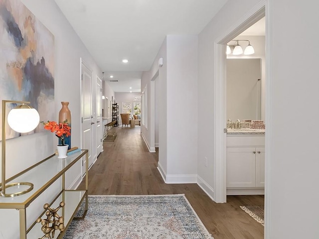 hallway featuring dark wood-type flooring, recessed lighting, and baseboards