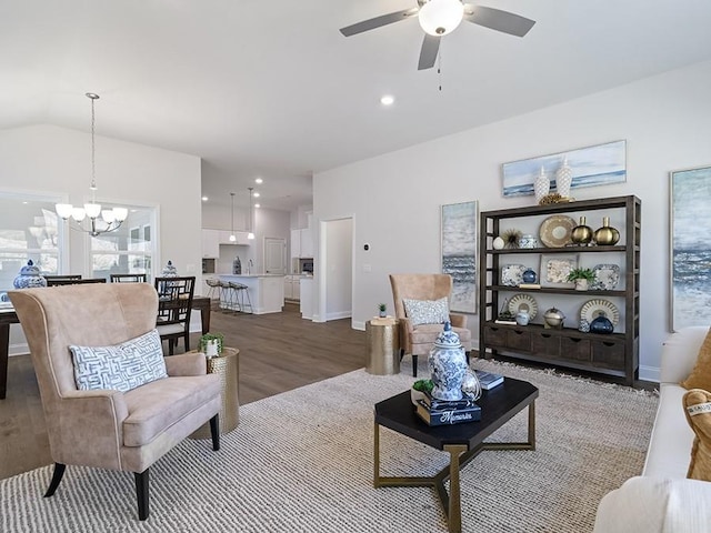 living room with baseboards, wood finished floors, ceiling fan with notable chandelier, vaulted ceiling, and recessed lighting