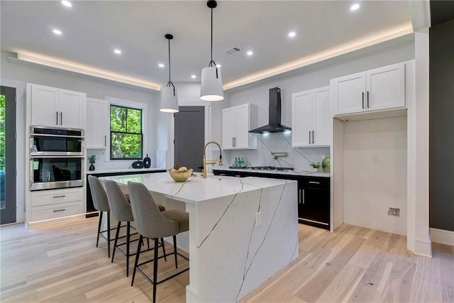 136 Beutell St, Norcross, GA 30071 - kitchen with wall chimney exhaust hood, a tray ceiling, appliances with stainless steel finishes, tasteful backsplash, and recessed lighting