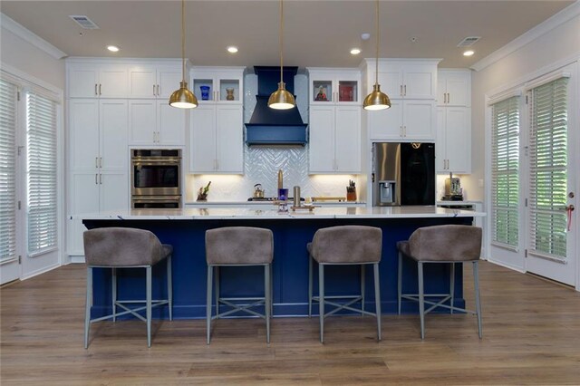 451 Burton Dr Unit 32, Alpharetta, GA 30009 - kitchen featuring appliances with stainless steel finishes, premium range hood, a large island with sink, crown molding, and white cabinetry