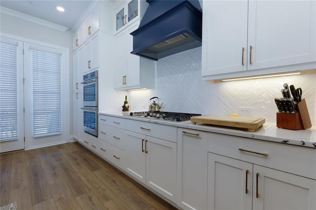 451 Burton Dr Unit 32, Alpharetta, GA 30009 - kitchen featuring custom range hood, gas cooktop, stainless steel double oven, decorative backsplash, and white cabinetry