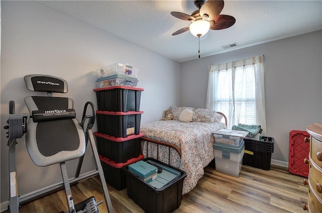 bedroom featuring hardwood / wood-style floors, a textured ceiling, and ceiling fan