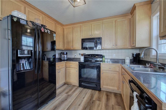 kitchen featuring light brown cabinetry, sink, backsplash, light hardwood / wood-style floors, and black appliances