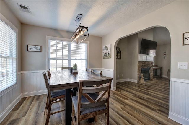 dining area with dark wood-type flooring, a fireplace, and a textured ceiling