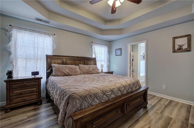 bedroom featuring a tray ceiling, wood-type flooring, and ceiling fan