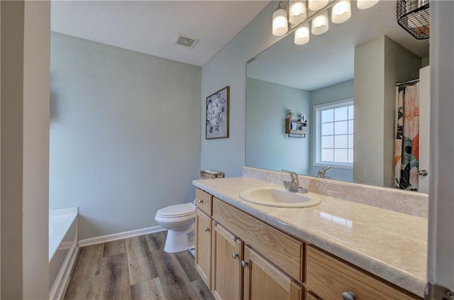 bathroom with vanity, a washtub, hardwood / wood-style flooring, and toilet