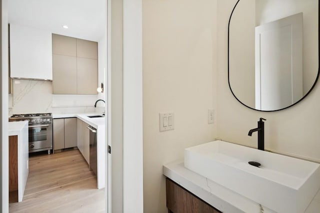 bathroom featuring recessed lighting, wood finished floors, vanity, and decorative backsplash