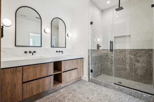 full bath featuring a sink, double vanity, baseboards, visible vents, and a shower stall