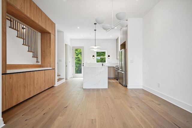 kitchen featuring light wood finished floors, modern cabinets, pendant lighting, high end fridge, and a kitchen island