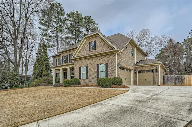 view of front of home featuring driveway, a garage, brick siding, fence, and a front yard