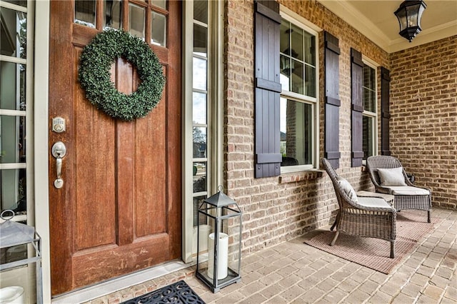 doorway to property with covered porch and brick siding