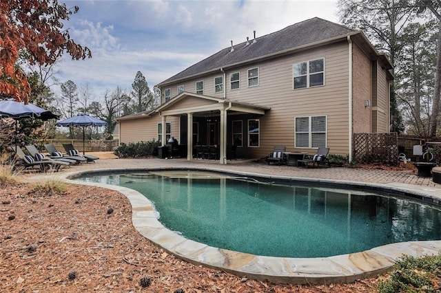 rear view of property with a fenced in pool, a patio, and fence