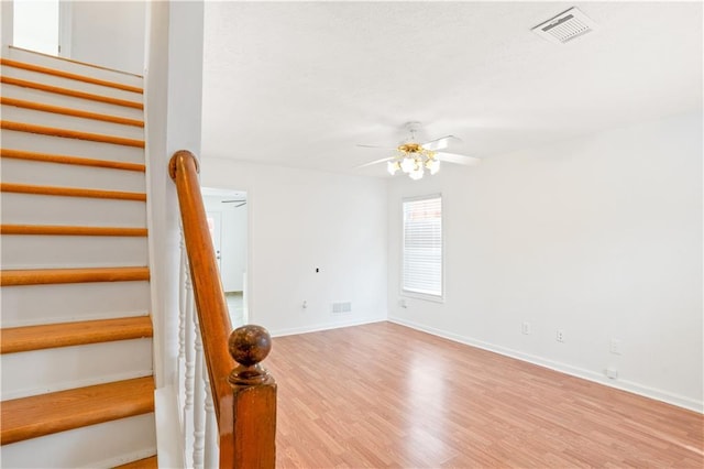 staircase featuring ceiling fan and hardwood / wood-style floors