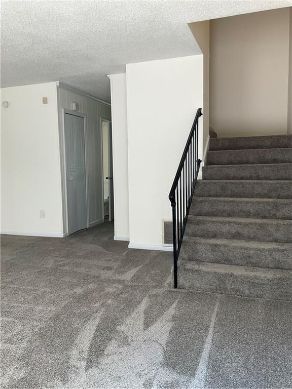 staircase with a textured ceiling and carpet floors