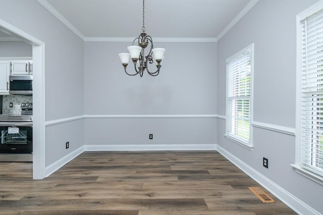 unfurnished dining area with an inviting chandelier, crown molding, and dark hardwood / wood-style flooring