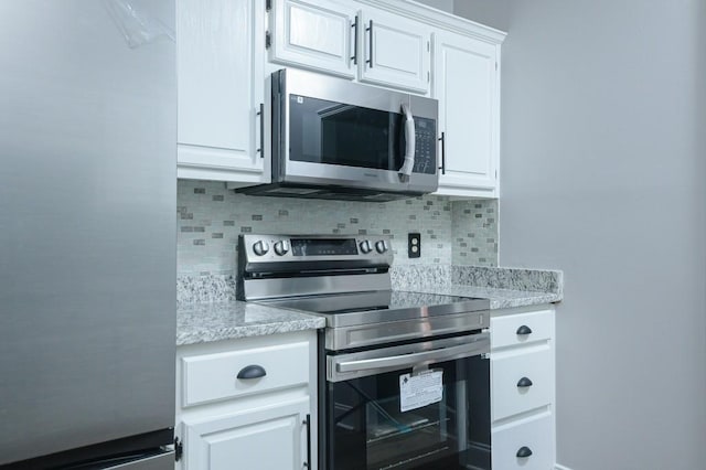 kitchen featuring decorative backsplash, white cabinetry, and appliances with stainless steel finishes