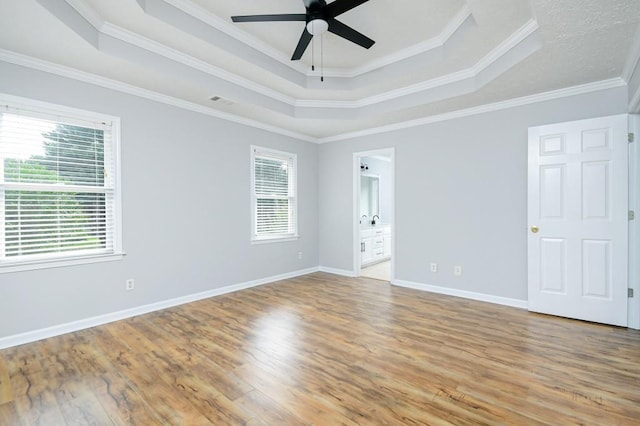 spare room featuring light wood-type flooring, a raised ceiling, ornamental molding, and ceiling fan