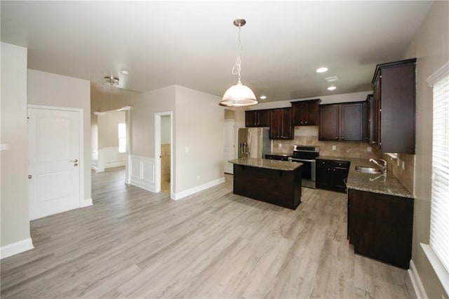 kitchen with stainless steel appliances, backsplash, light hardwood / wood-style floors, decorative light fixtures, and a kitchen island