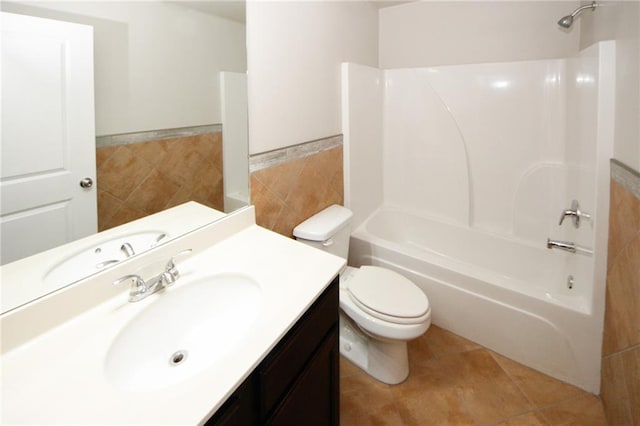 full bathroom featuring washtub / shower combination, vanity, tile walls, tile patterned flooring, and toilet