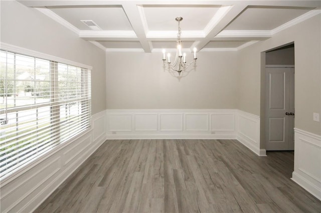 empty room featuring ornamental molding, coffered ceiling, dark wood-type flooring, beam ceiling, and a notable chandelier