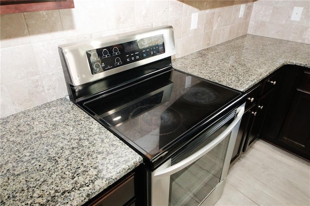 kitchen featuring decorative backsplash, light stone counters, tile walls, and stainless steel range with electric cooktop