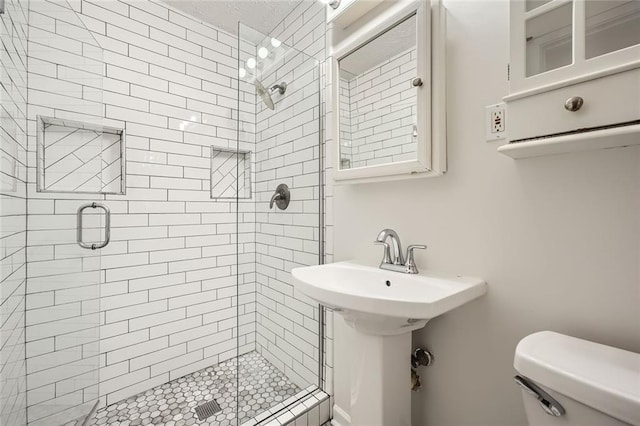 bathroom with sink, a shower with shower door, and toilet