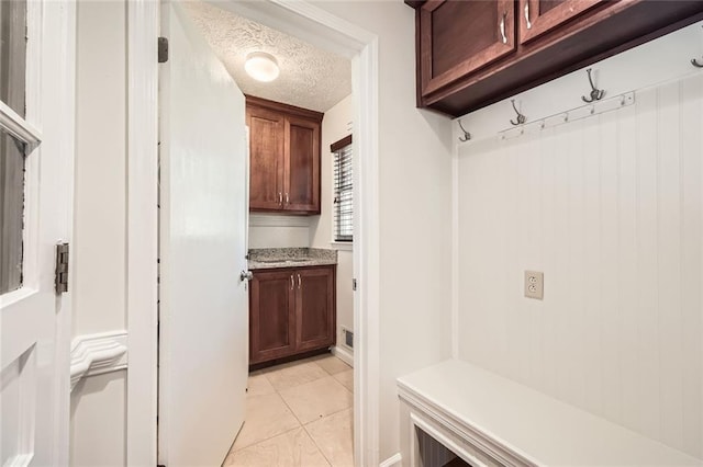 mudroom with a textured ceiling and light tile patterned floors