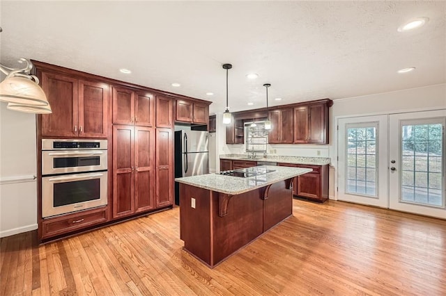 kitchen featuring a center island, decorative light fixtures, french doors, appliances with stainless steel finishes, and a kitchen breakfast bar