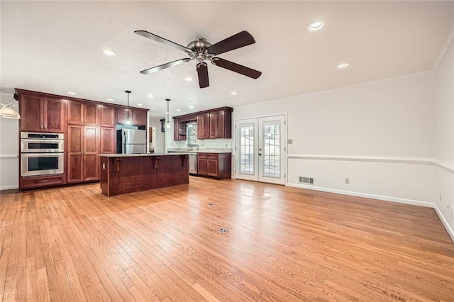 kitchen featuring appliances with stainless steel finishes, a center island, pendant lighting, french doors, and a kitchen bar