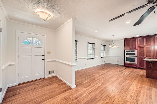 entryway featuring ceiling fan with notable chandelier, light wood-type flooring, ornamental molding, and a textured ceiling