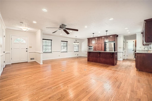 kitchen with appliances with stainless steel finishes, a center island, ceiling fan, a kitchen bar, and decorative light fixtures