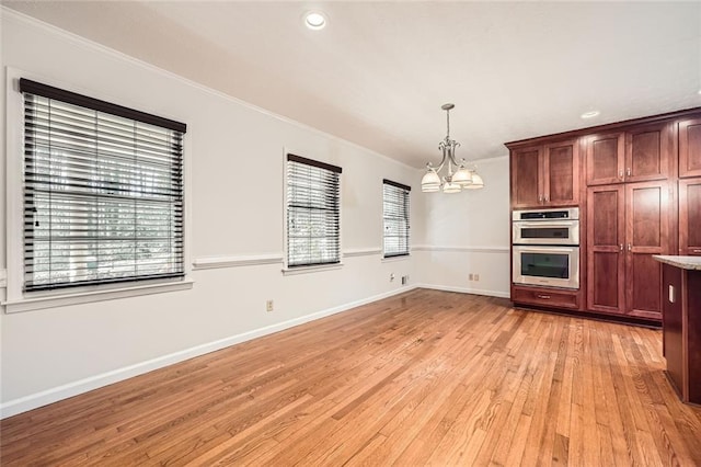 kitchen featuring ornamental molding, light wood-type flooring, hanging light fixtures, double oven, and a notable chandelier