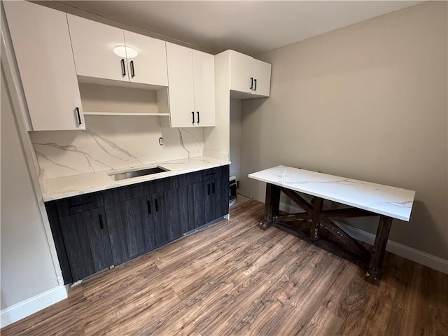 kitchen with sink, white cabinetry, wood-type flooring, and backsplash