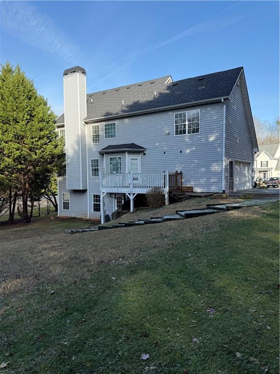 back of house featuring a deck, a yard, and a garage