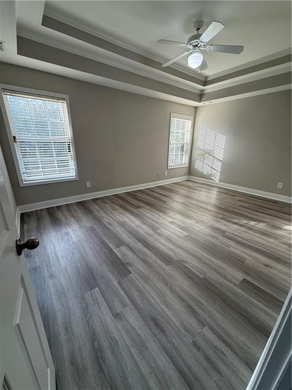 spare room featuring ceiling fan, a tray ceiling, dark wood-type flooring, and ornamental molding