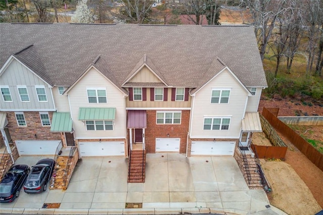 view of front facade featuring a garage, driveway, fence, and brick siding