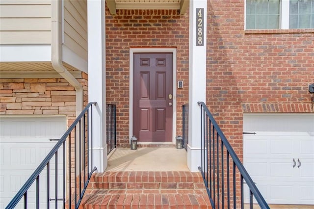 view of exterior entry with a garage and brick siding