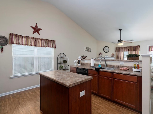 kitchen with a center island with sink, sink, vaulted ceiling, ceiling fan, and wood-type flooring