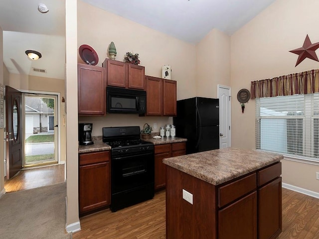 kitchen featuring black appliances, a kitchen island, and light hardwood / wood-style flooring