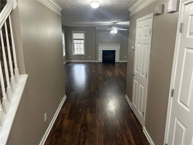 hall with ornamental molding, dark wood-type flooring, and a textured ceiling