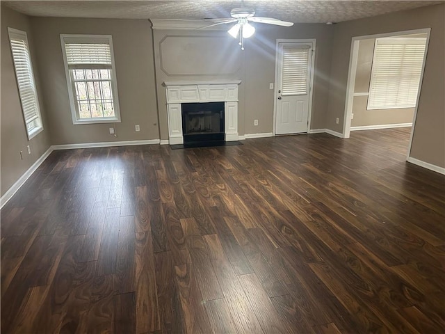 unfurnished living room with ceiling fan, dark hardwood / wood-style floors, and a textured ceiling