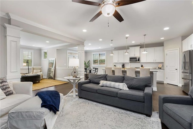 living area with ceiling fan, recessed lighting, dark wood-type flooring, ornate columns, and crown molding